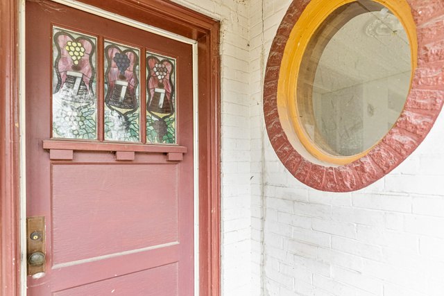 Original front door with stained glass panels beside a round porthole window